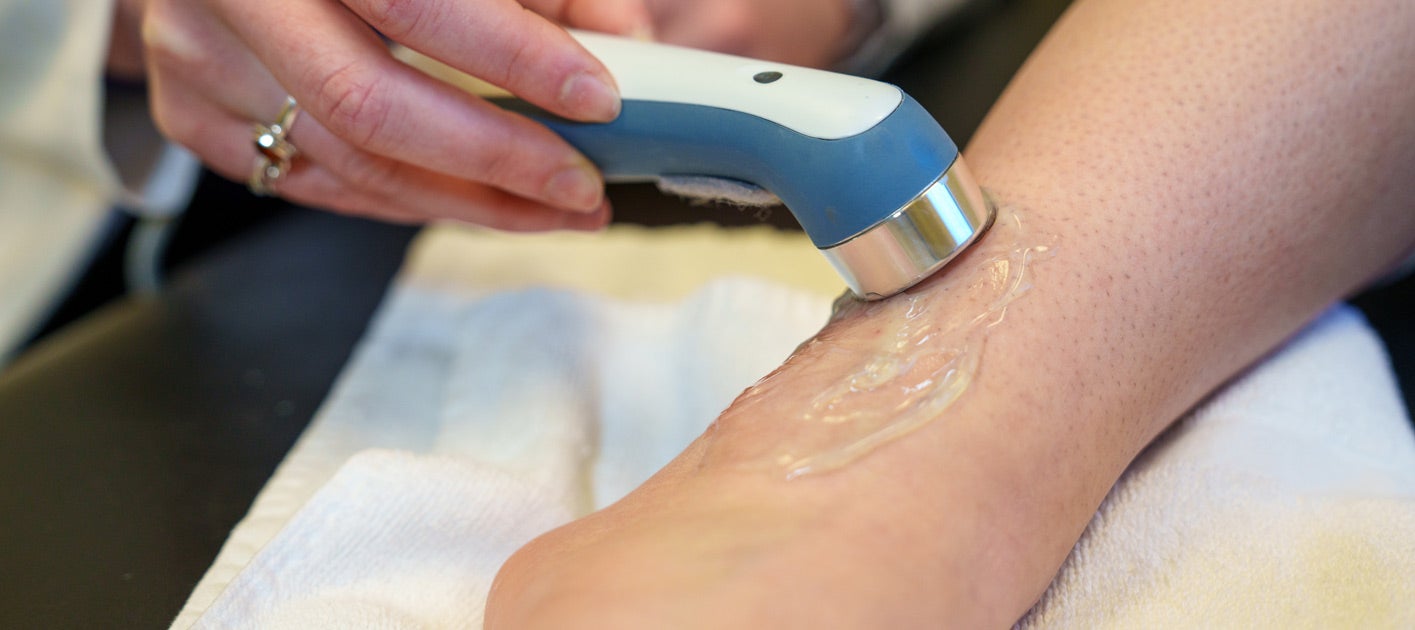 Clinician using ultrasound on client's ankle and leg.